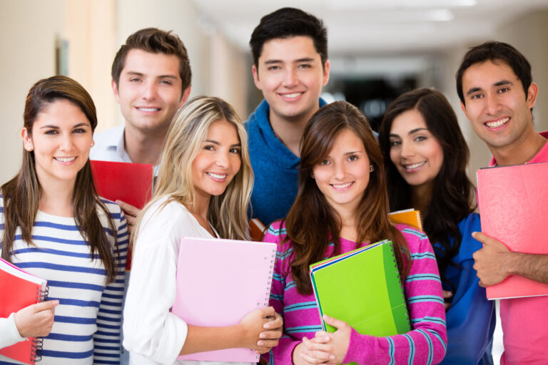 Marketing para atrair alunos: imagem mostra grupo de estudantes sorrindo e segurando cadernos.