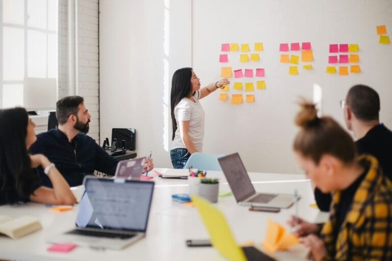 Comunicação escolar: imagem mostra pessoas em uma sala de reunião com quadro de informações.