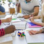 Gestores e professores reunidos em mesa de reuniões para elaborar o planejamento pedagógico.