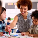 Professora negra com cabelos cacheados sorridente enquanto ensina seus alunos