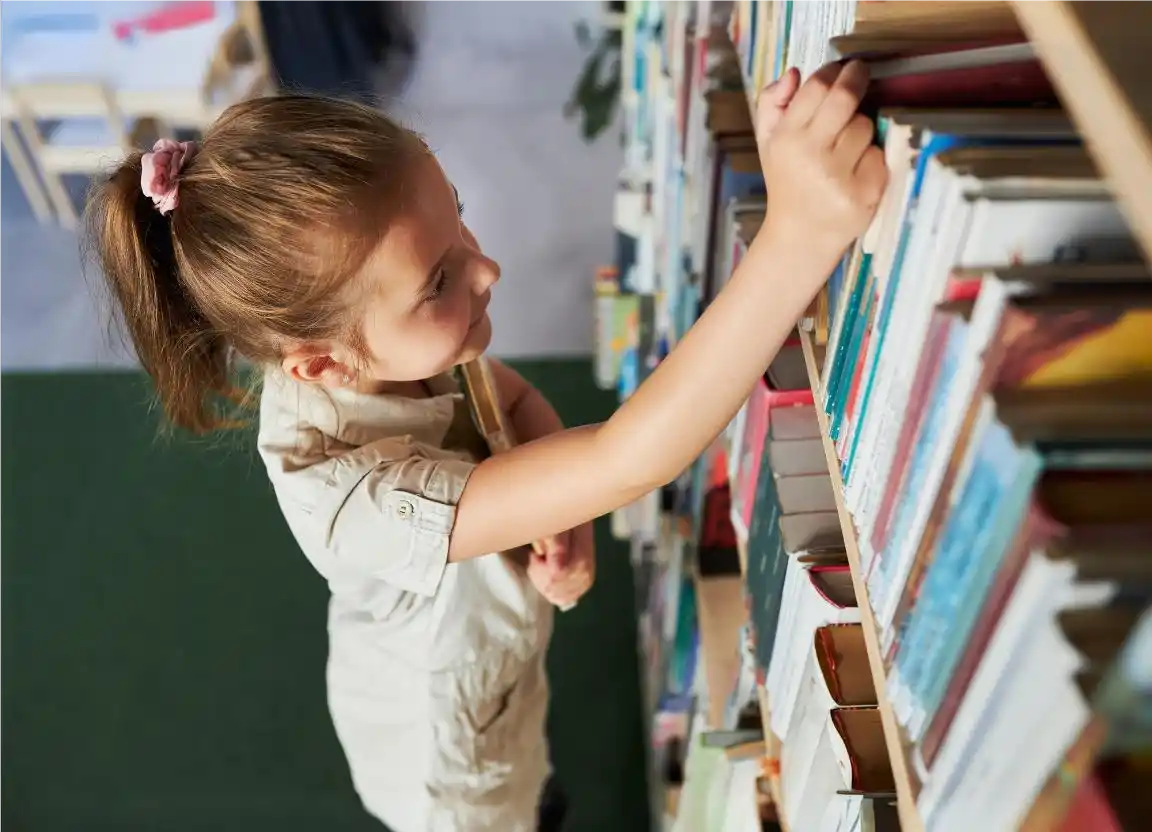 Criança em biblioteca no fim do período letivo