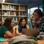 Três meninas sorridentes na biblioteca, alunos da novo Ensino Médio