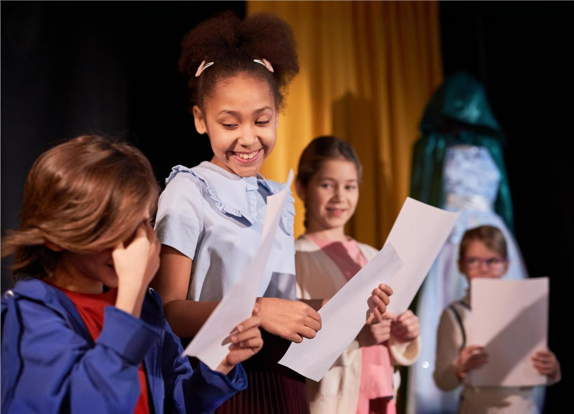 Duas meninas e dois meninos ensaiando para o teatro na escola