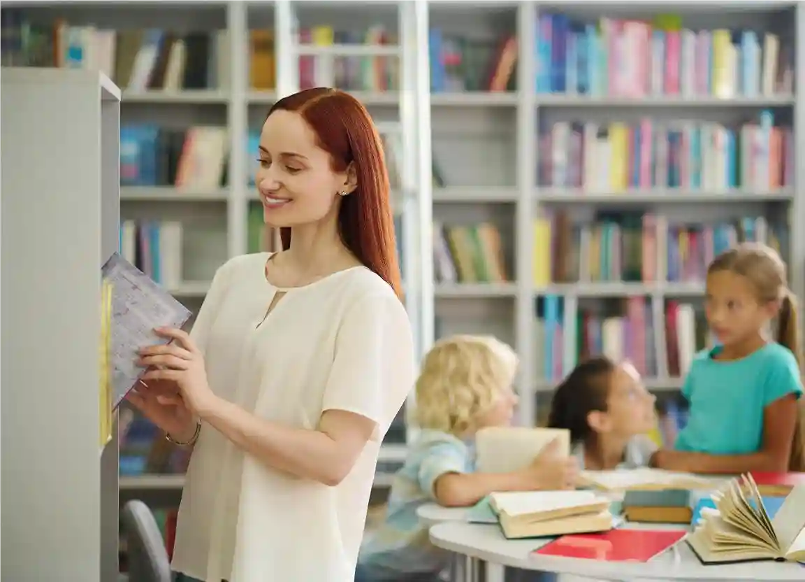 Profissional como orientador escolar em biblioteca, acompanhando os alunos